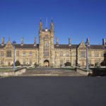 Large old brown university building with blue sky in the background.