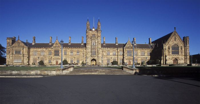 Large old brown university building with blue sky in the background.